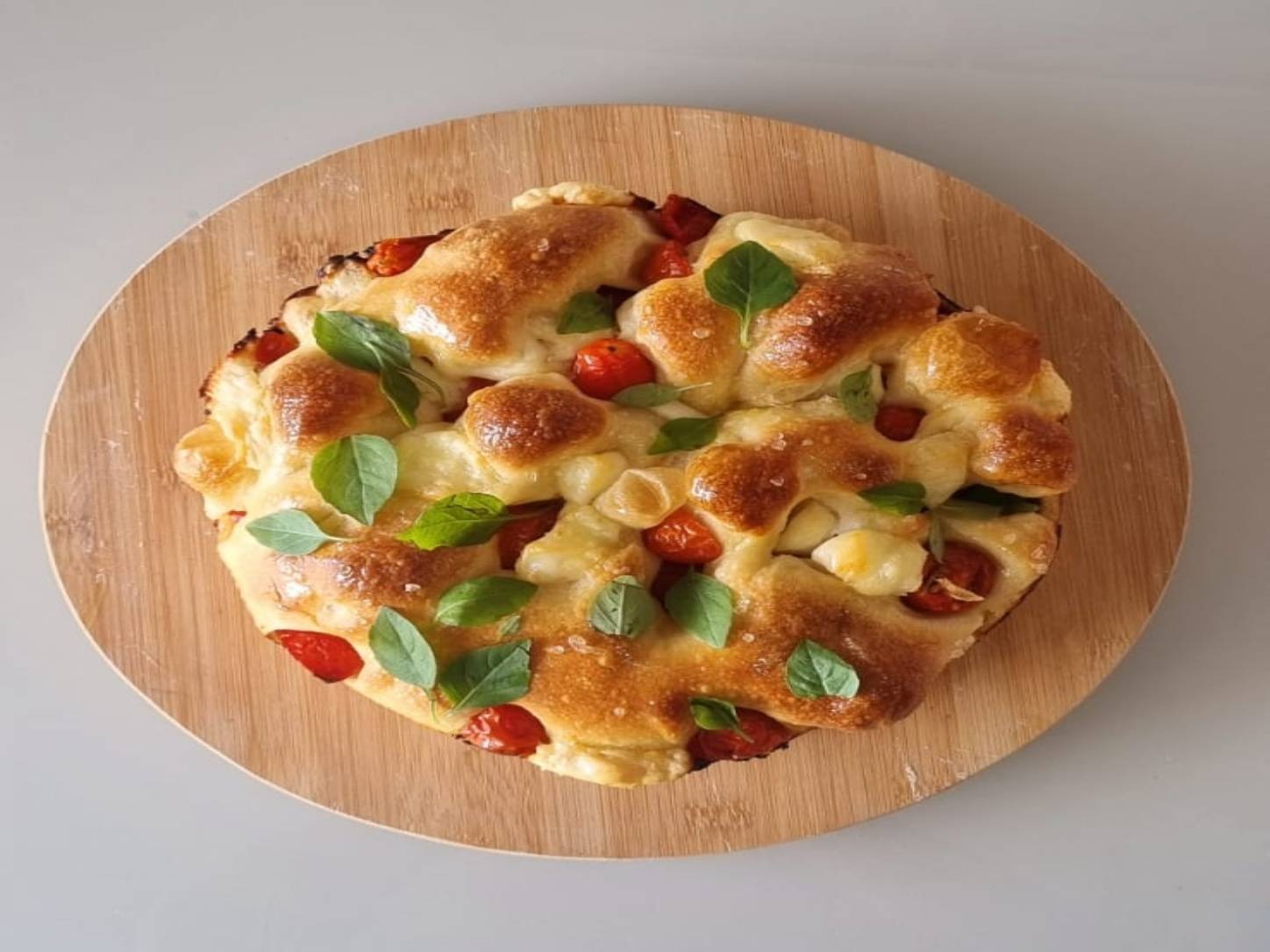 Focaccia com Muçarela de Búfala e Tomate Mel da Padoca da Joy, com tomates coloridos e queijo fresco sobre massa dourada