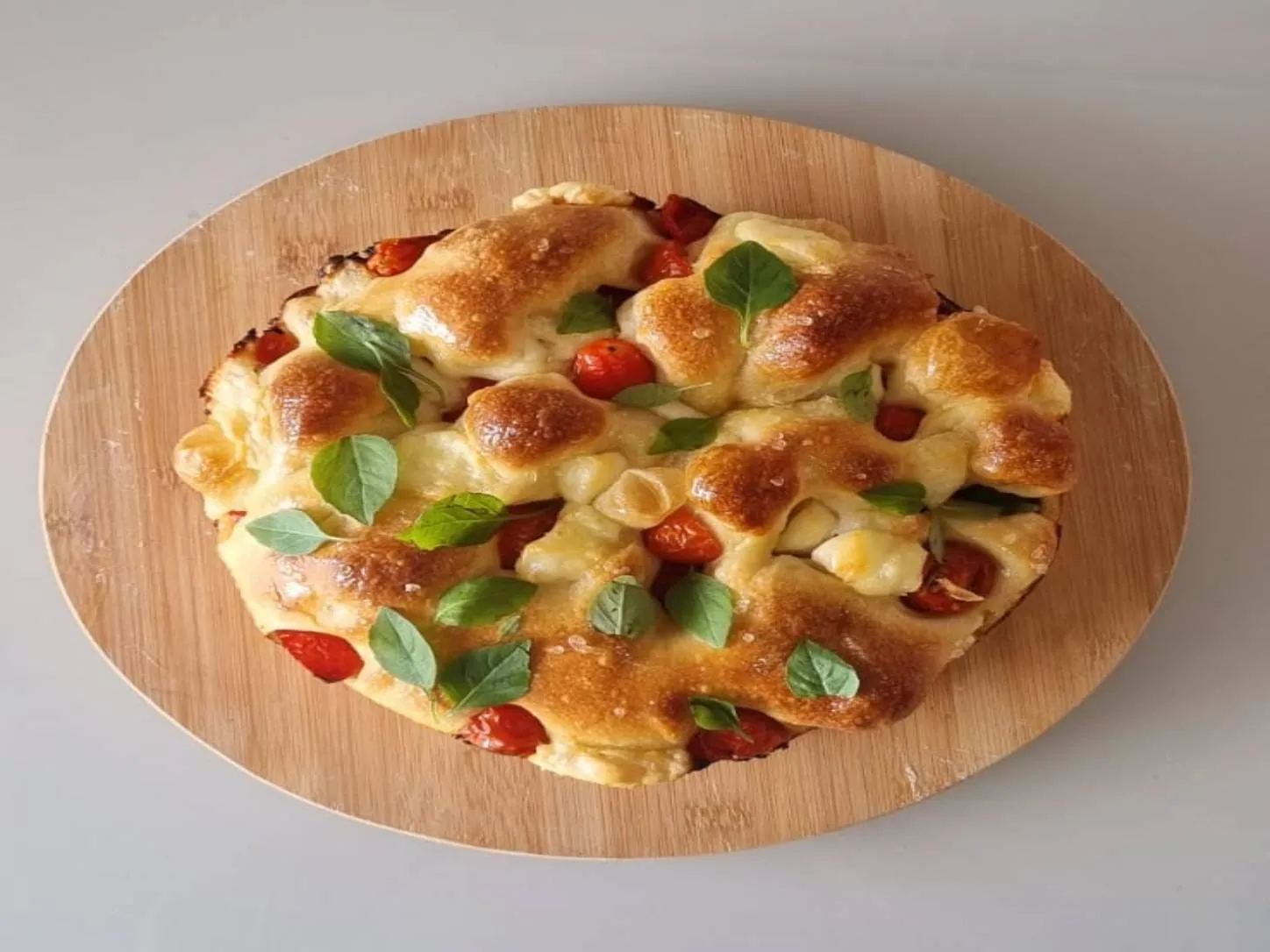 Focaccia com Muçarela de Búfala e Tomate Mel da Padoca da Joy, com tomates coloridos e queijo fresco sobre massa dourada