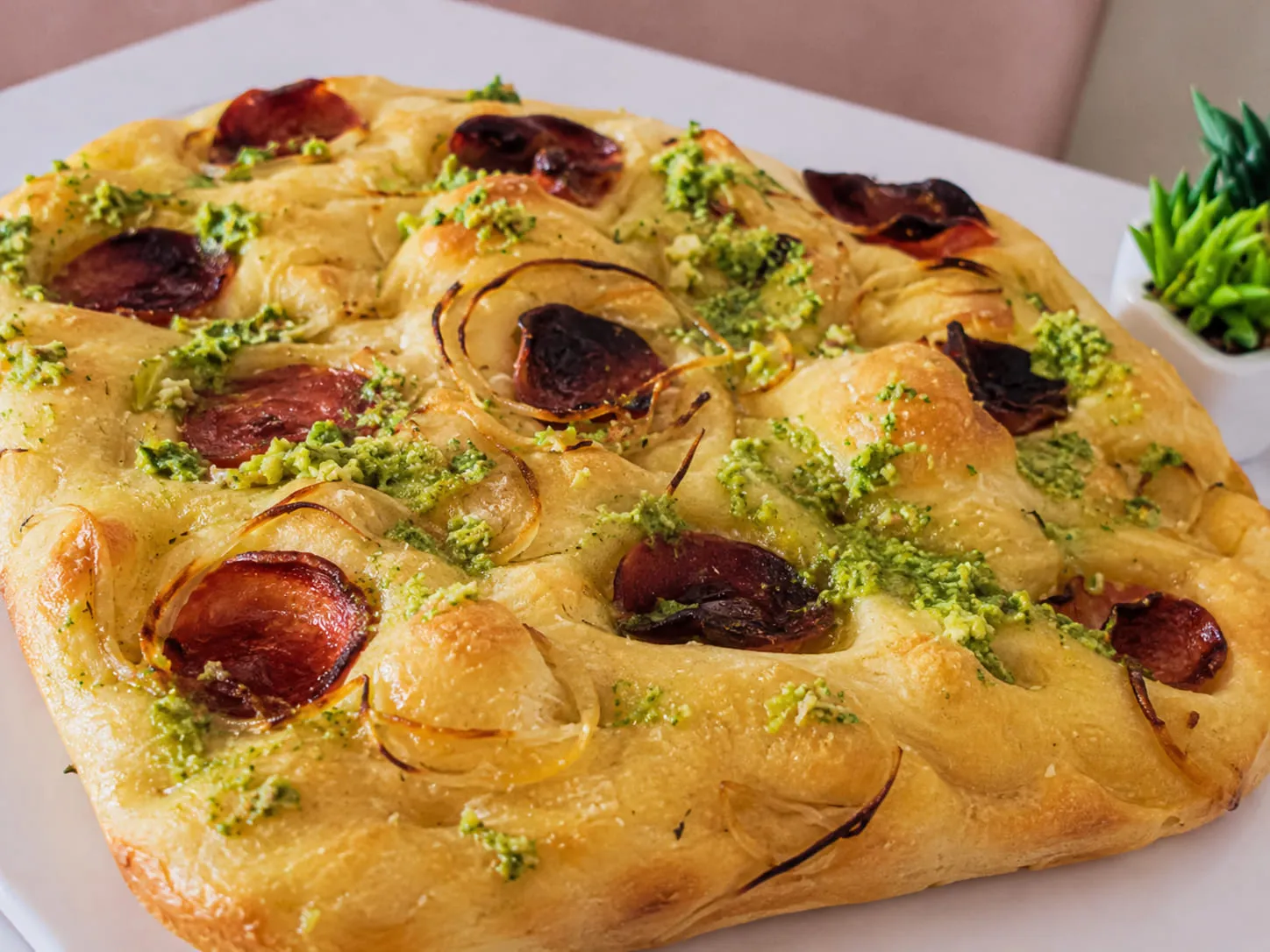 Focaccia Pepperoni com Pesto da Padoca da Joy, coberta com rodelas de pepperoni e molho pesto verde vibrante
