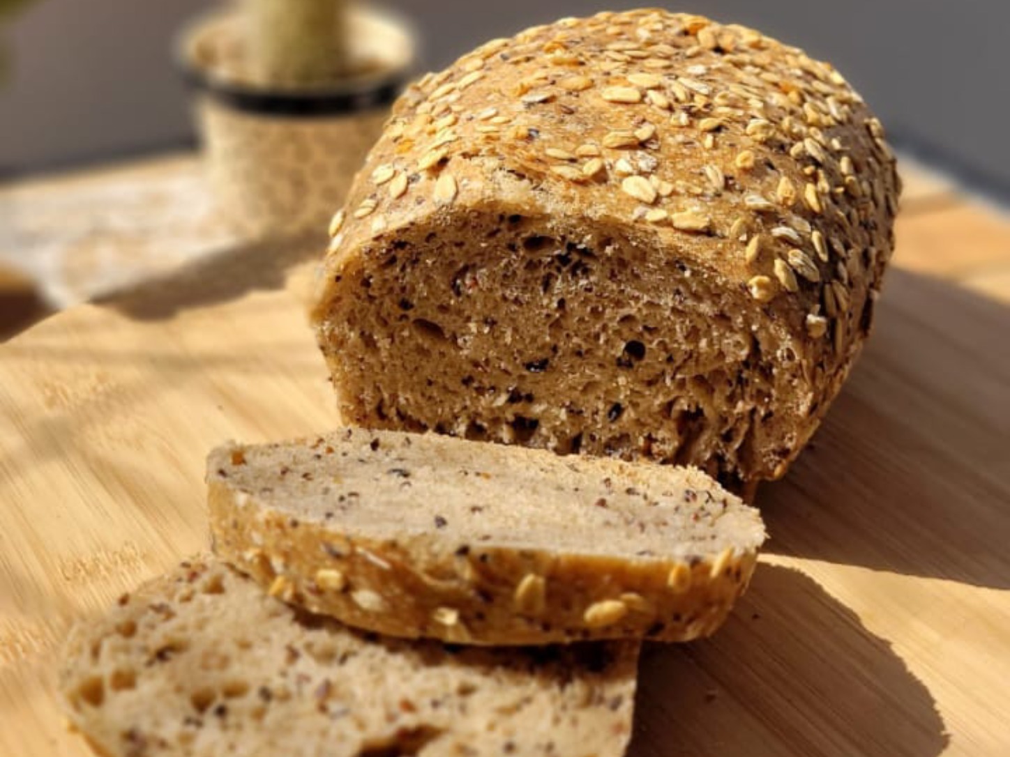 Pão de Forma Multigrãos Integral da Padoca da Joy, fatiado mostrando o miolo escuro e rico em grãos