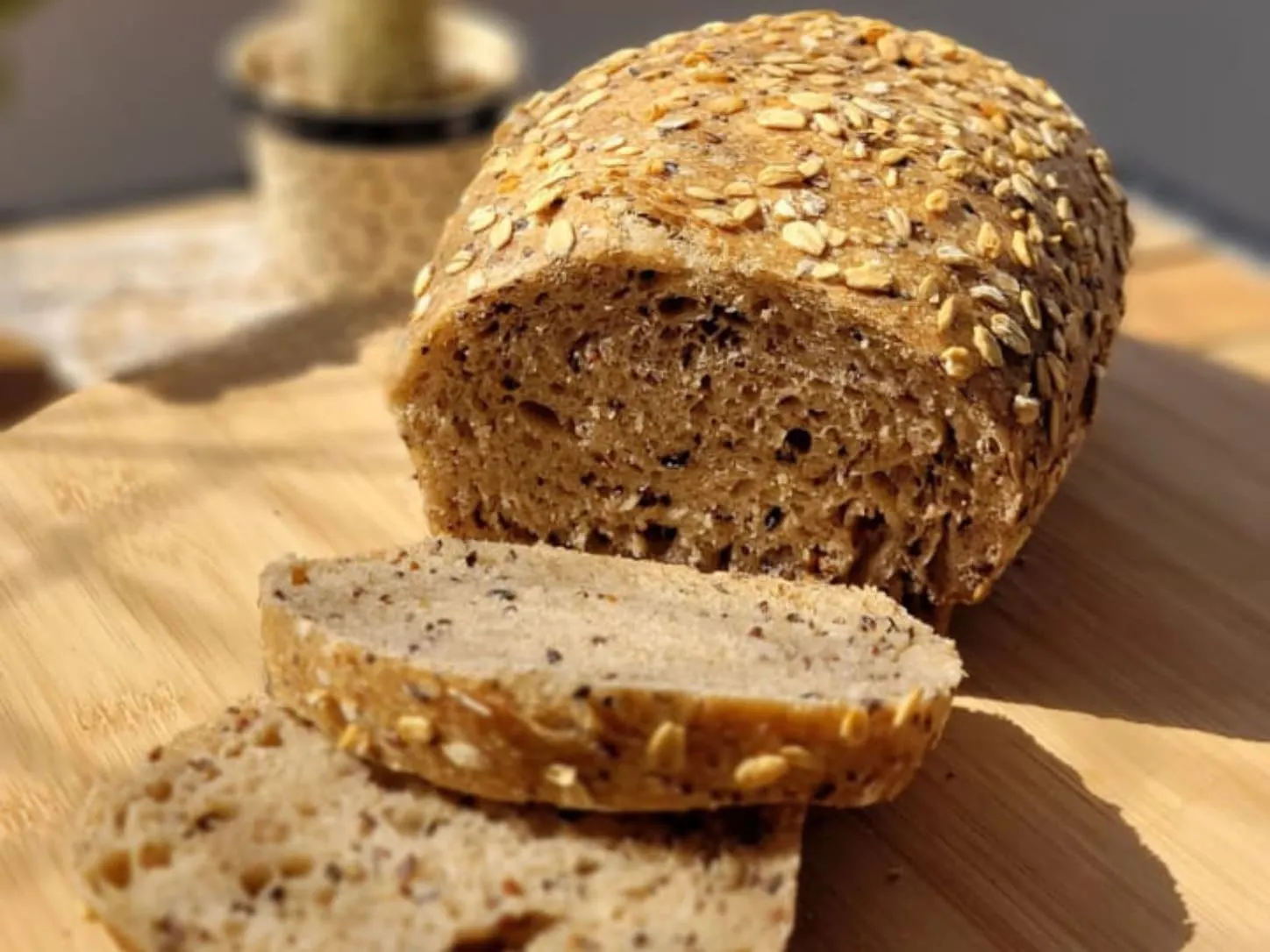 Pão de Forma Multigrãos Integral da Padoca da Joy, fatiado mostrando o miolo escuro e rico em grãos