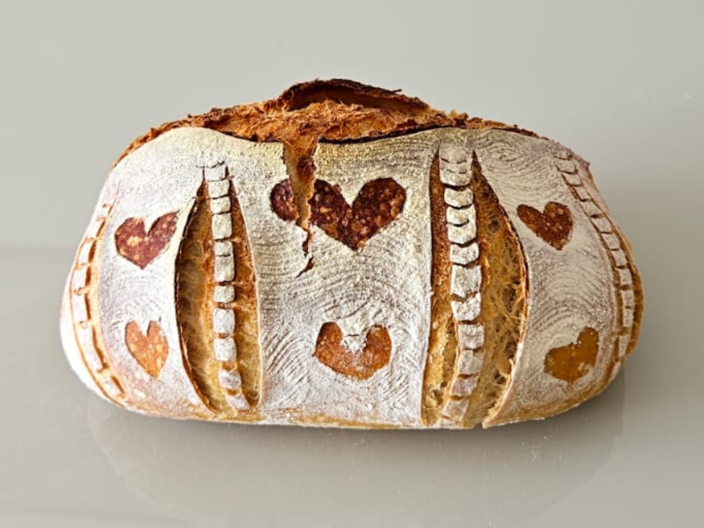 Pão Rústico artesanal da Padoca da Joy, com scoring decorativo em formato de coração e casca dourada