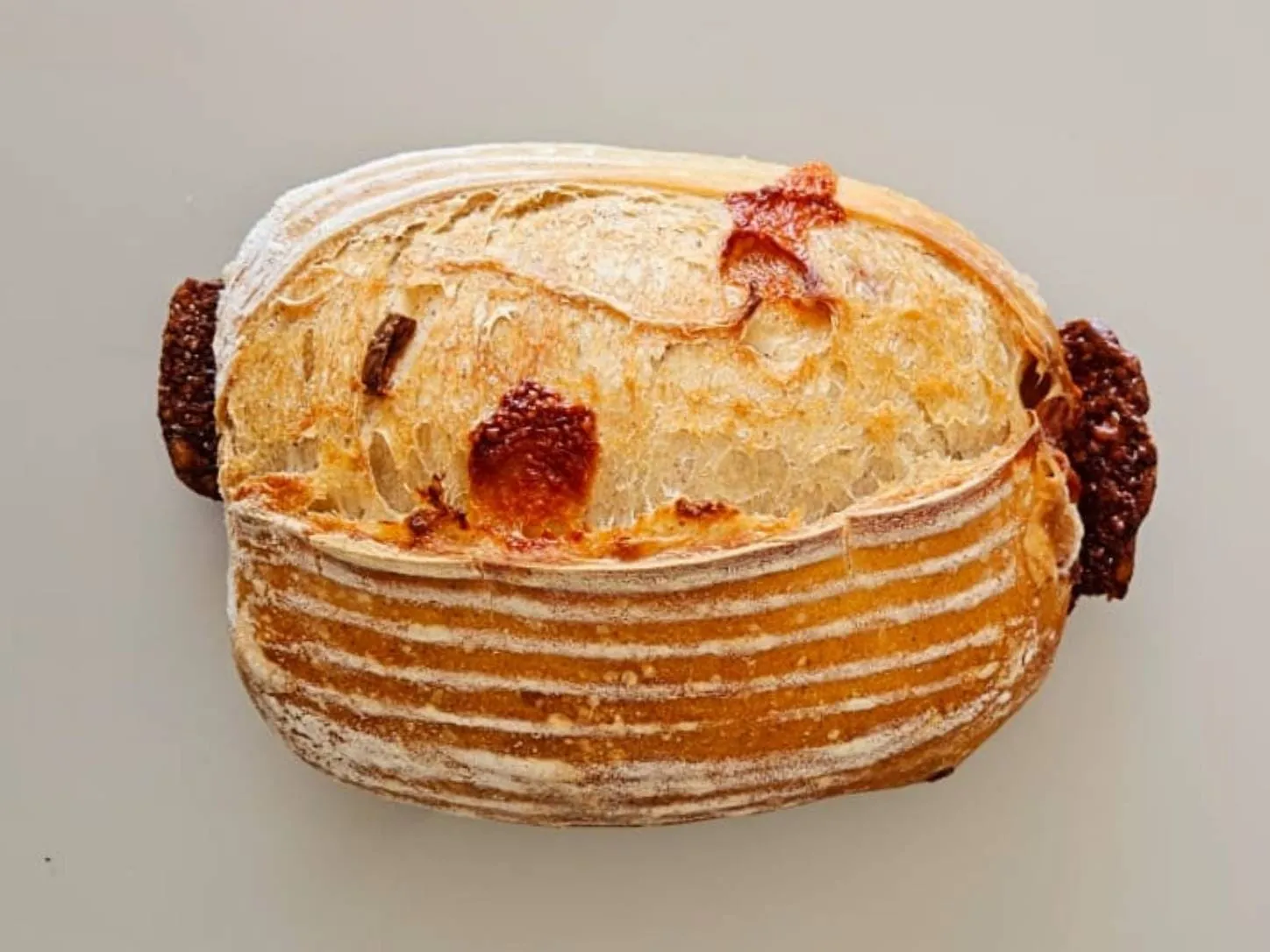 Sourdough Provolone da Padoca da Joy, com queijo derretendo pelas rachaduras do scoring da casca rústica